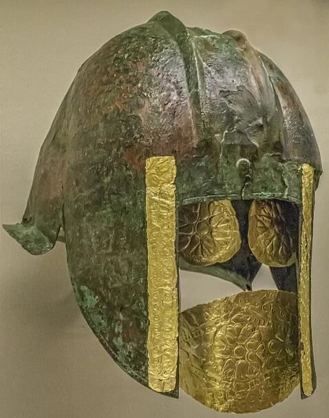 Funerary bronze helmet with gold eye and mouth pieces from the necropolis at Archontiko Greek 540-530 BCE. The deceased warrior was found lying on his back holding a gilded sword in his right hand, which bore a gold ring. A large embossed rosette, o